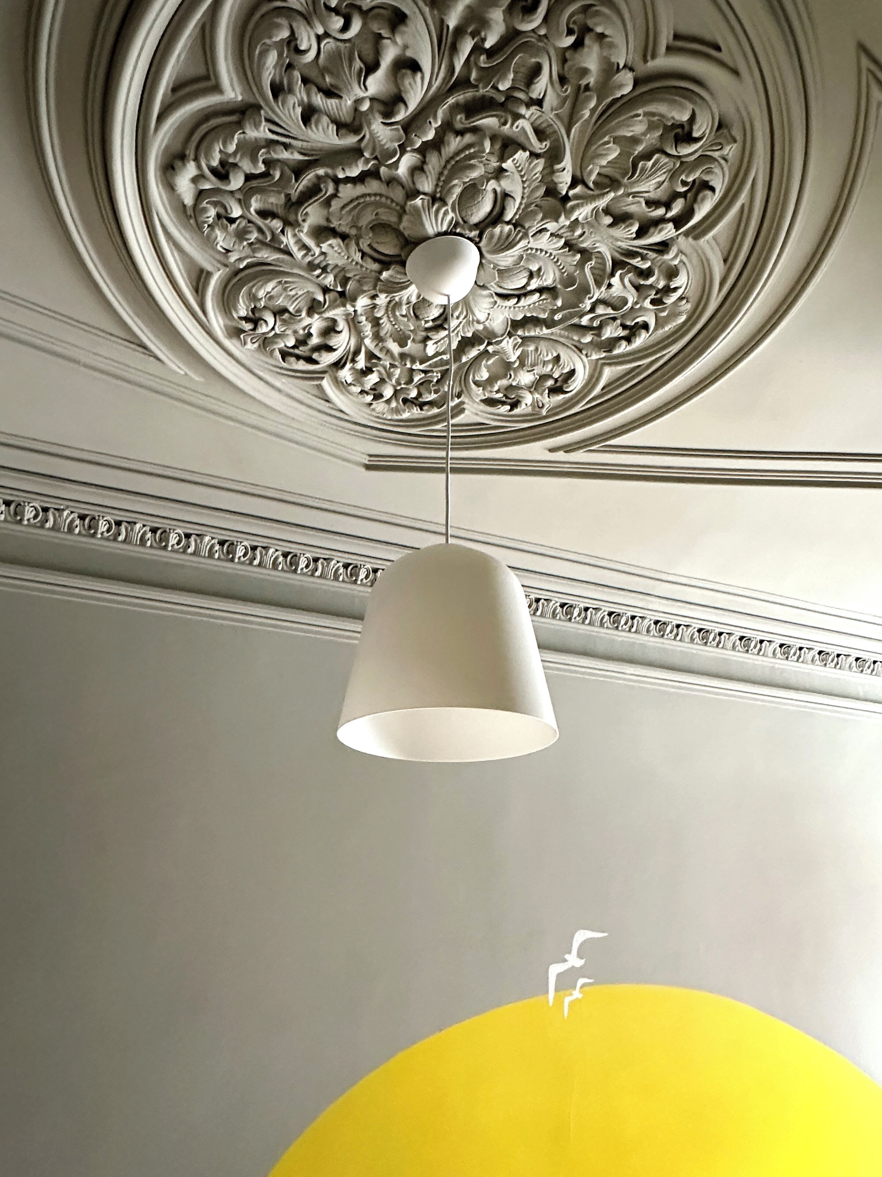 A ceiling with ornate carvings and a hanging light fixture.