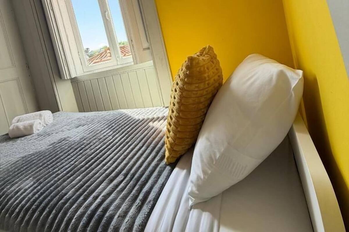 A bed with a striped bedspread, a white pillow, and a textured pillow.