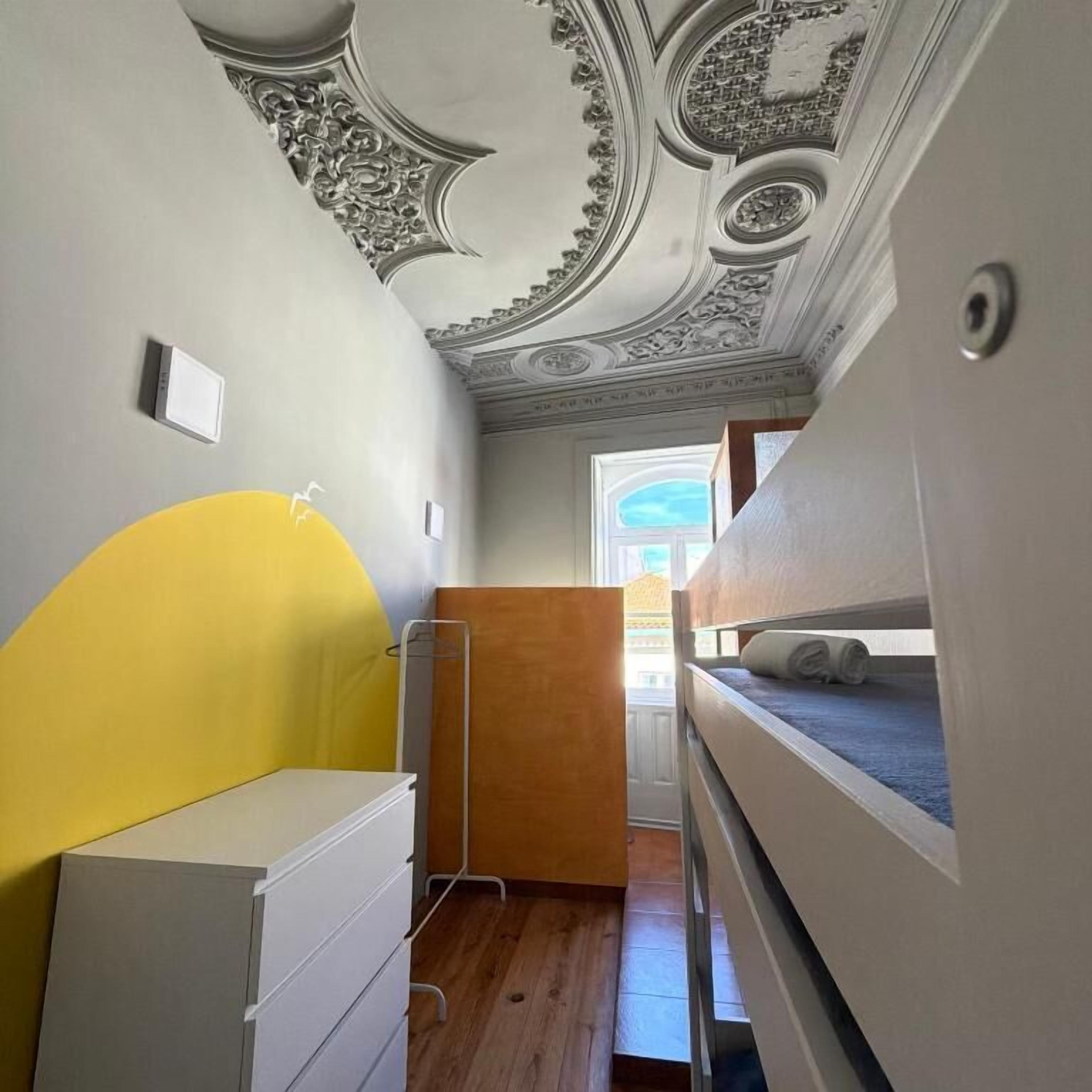 A room with a bunk bed, a white dresser, and a decorative ceiling.