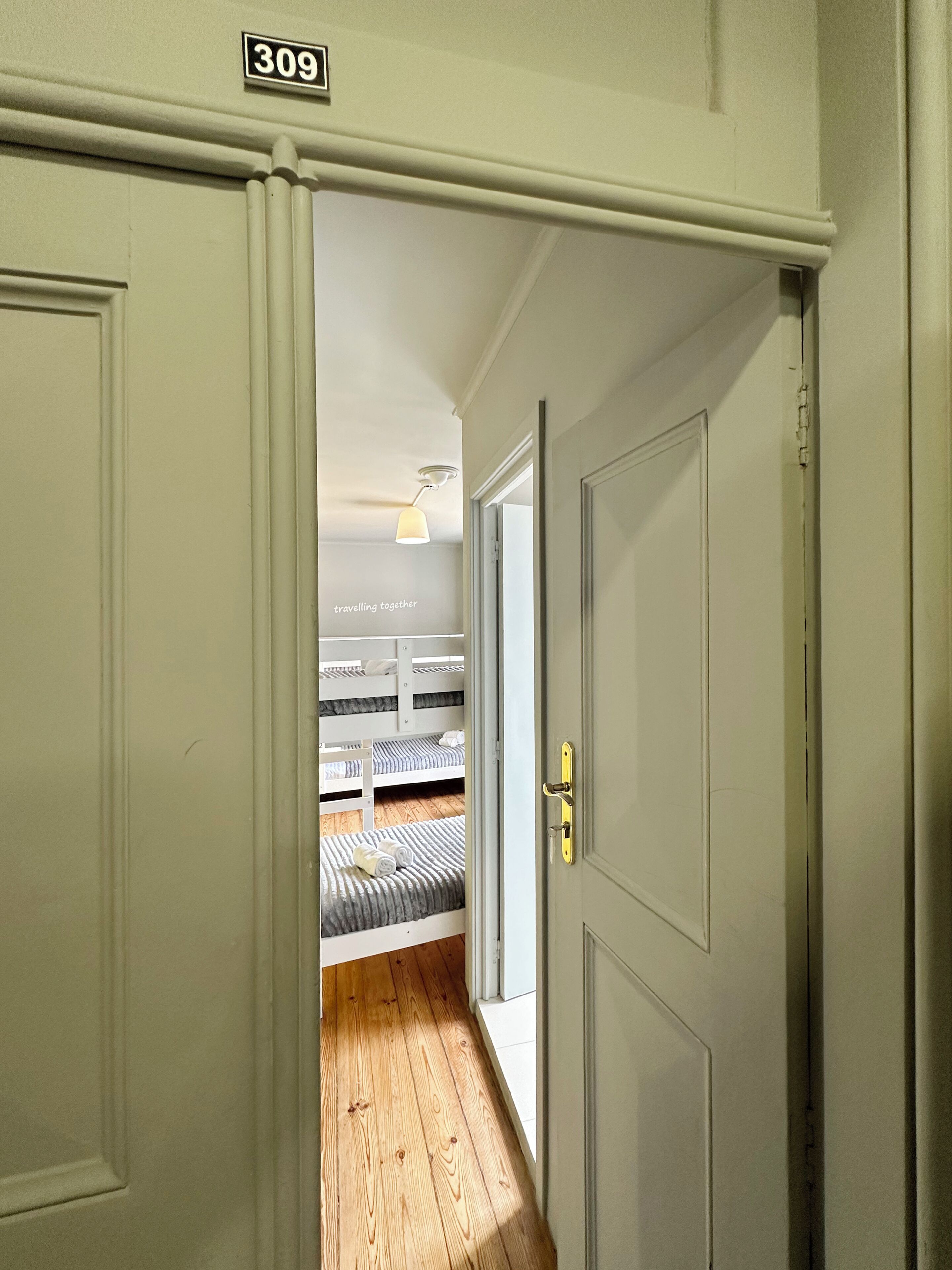A hallway with a door labeled '309' leading to a room with bunk beds.