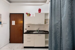 Een kleine keuken met een spoelbak, kastjes en een deur.
