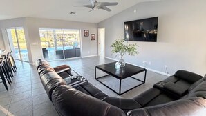 A spacious living room with a sectional sofa, a coffee table, and a TV mounted on the wall. - Relaxing House with Gulf Access & Heated Pool (Cape Coral)