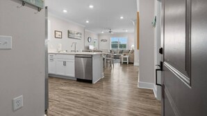 Una cocina moderna con una isla central, un comedor con mesa y sillas, y una sala de estar con sofá.