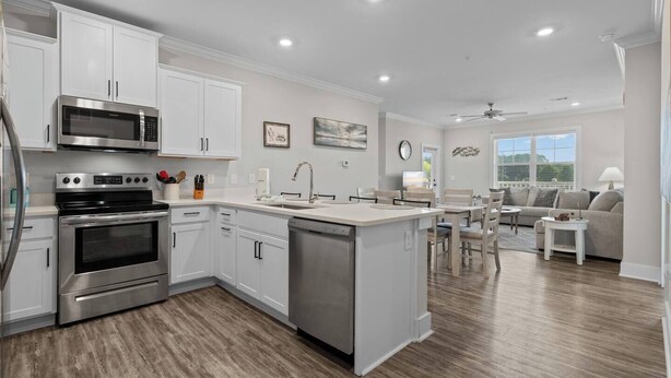 Una cocina moderna con electrodomésticos de acero inoxidable, una isla central y un área de comedor con sofá y mesa.