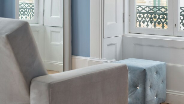 A room with a large window, a white door, and a blue ottoman. - Aveiro History Apartments (Aveiro)