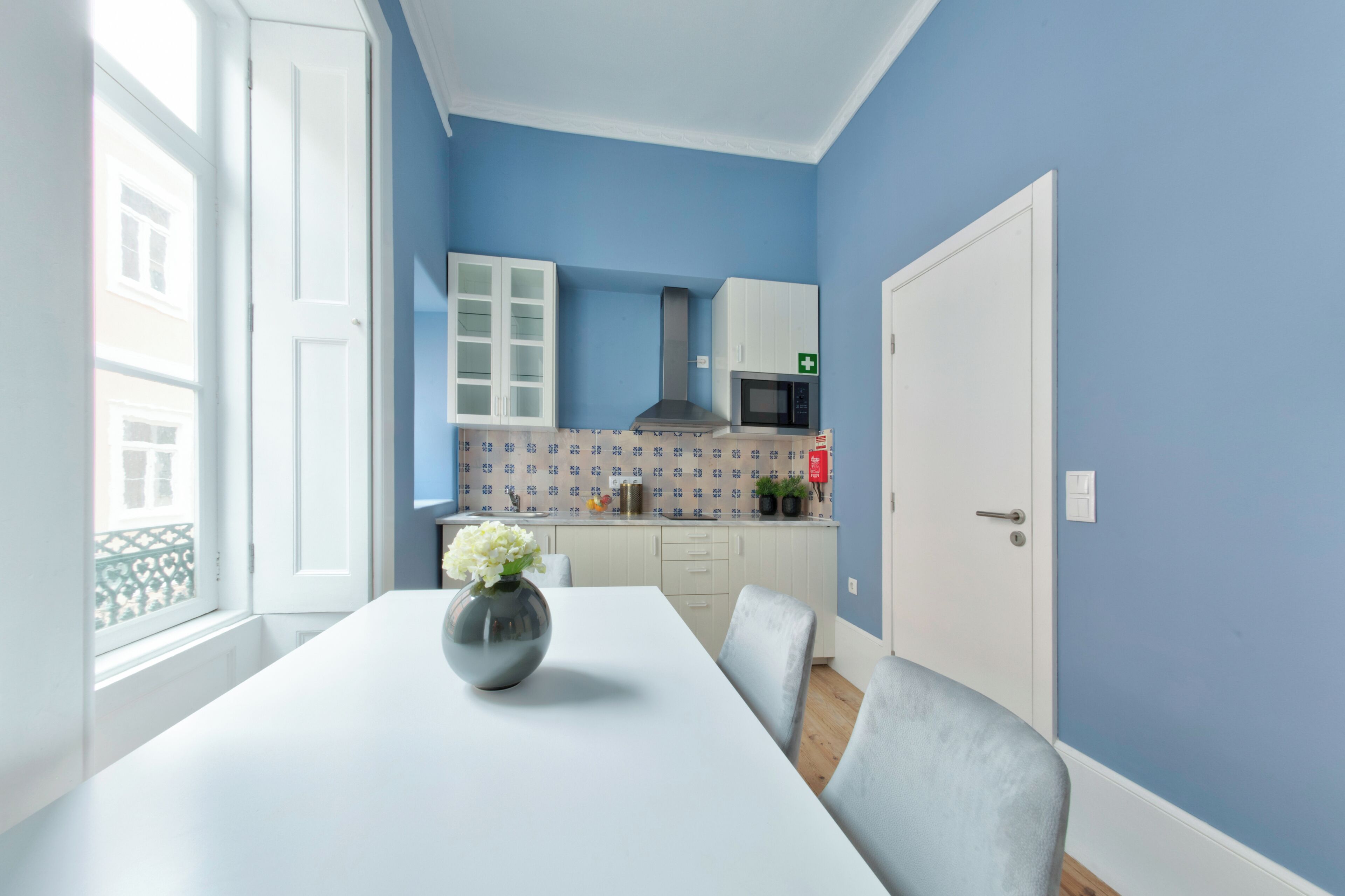 Een kamer met een witte tafel, een bloemenvaas, een magnetron en een kast.