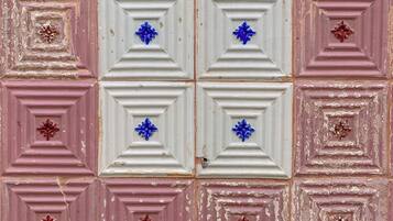 Una pared con diseño que alterna baldosas cuadradas en rosa y blanco, algunas con motivos florales.