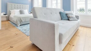 A bedroom with a bed, a white sofa, and a large window. - Aveiro History Apartments (Aveiro)