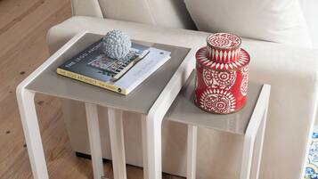 A modern living room with a sofa, a side table with a book titled 'The LEGO Architect' and a decorative item.