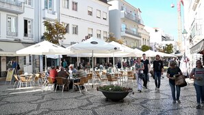 An outdoor café area with tables and chairs, surrounded by buildings with balconies. - Aveiro History Apartments (Aveiro)
