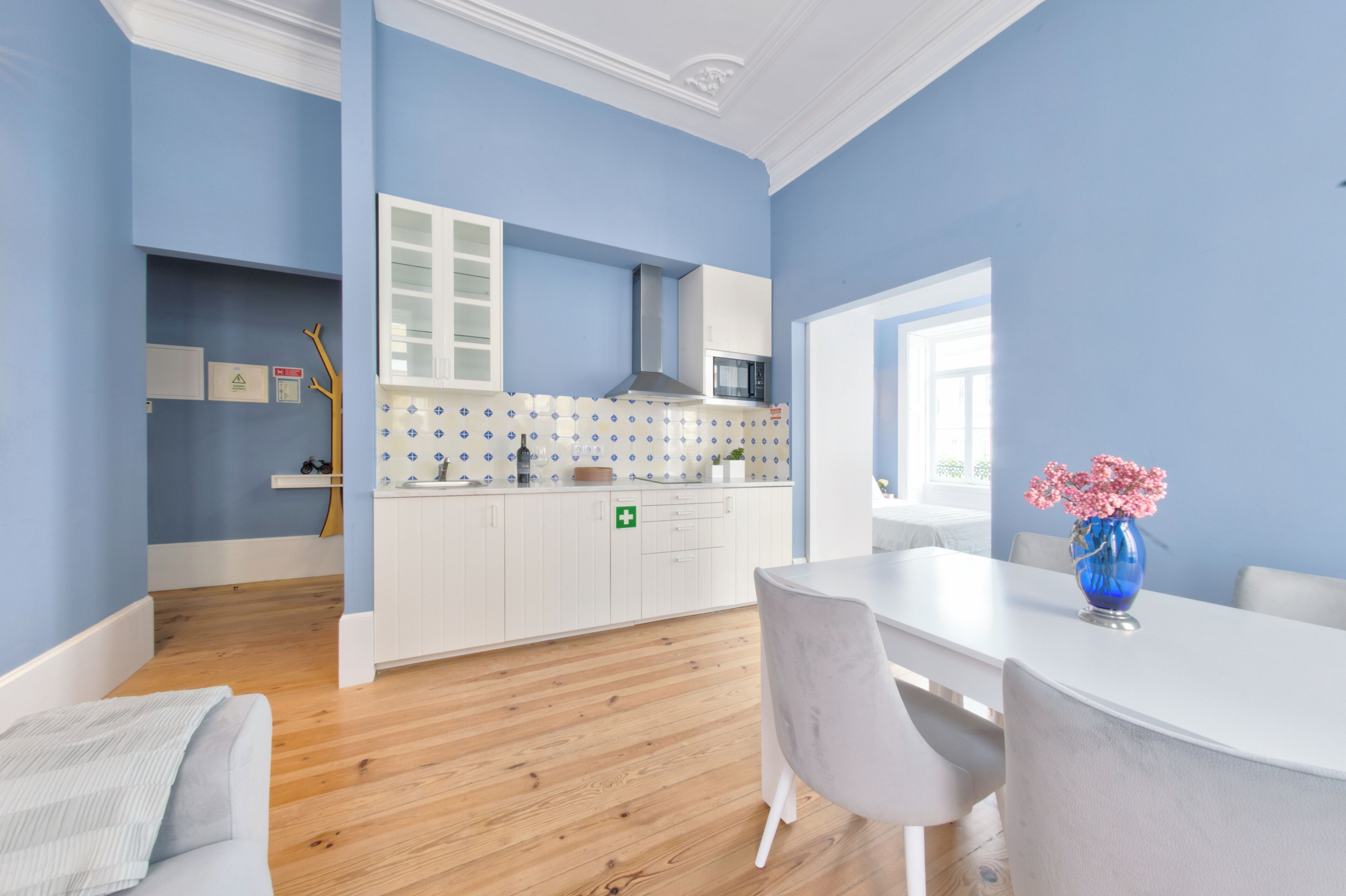 A modern kitchen with white cabinets, a microwave, and a blue wall.