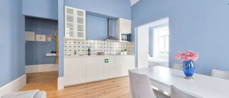 Una cocina moderna con armarios blancos, un microondas y una pared azul.