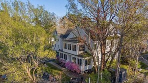 A two-story house with a front porch, surrounded by trees and a garden. - Private Coastal 4 BD Getaway in Ocean Park ME (Old Orchard Beach)