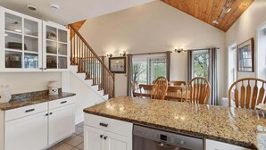 A kitchen with white cabinets, a granite countertop, a Bosch dishwasher, and a wooden staircase. - Private Coastal 4 BD Getaway in Ocean Park ME (Old Orchard Beach)