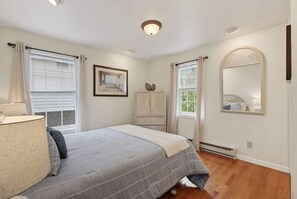 A bedroom with a bed, a bedside lamp, a dresser, a mirror, and a window with blinds. - Private Coastal 4 BD Getaway in Ocean Park ME (Old Orchard Beach)