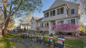 A two-story house with a stone pathway leading to outdoor seating.