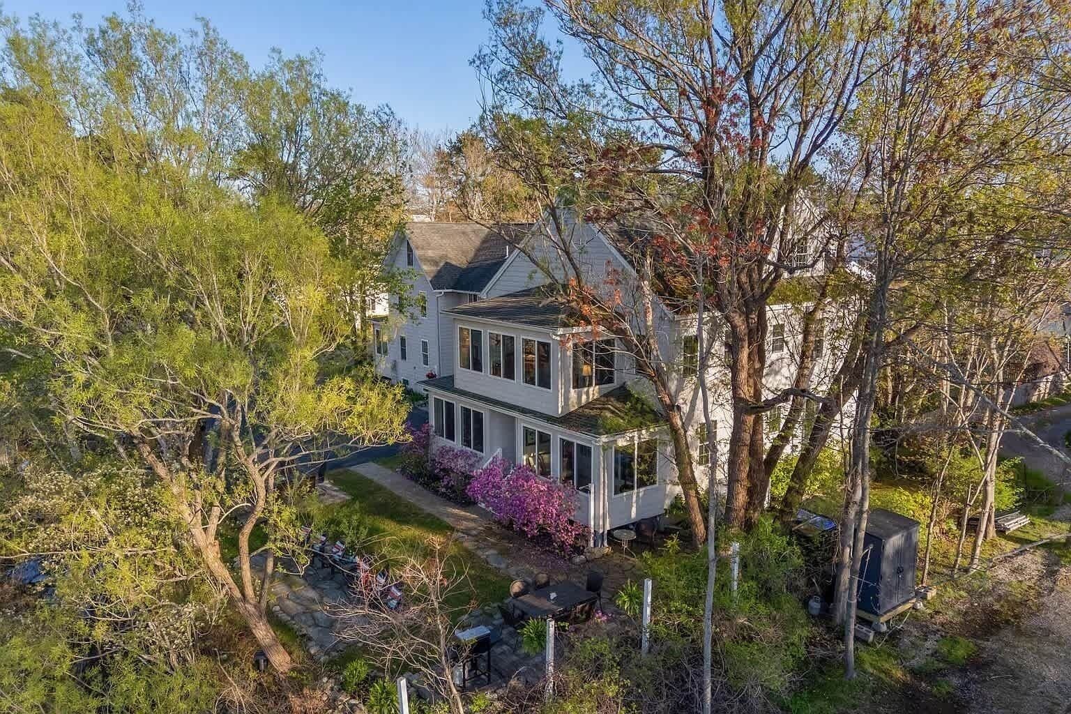 A two-story house with a front porch, surrounded by trees and a garden.