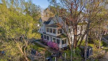 A two-story house with a front porch, surrounded by trees and a garden.