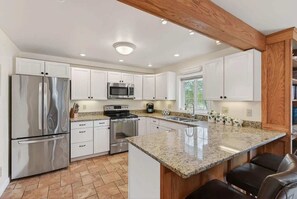 A modern kitchen with white cabinets, stainless steel appliances, and a granite countertop. - Private Coastal 2 BD Residence in Ocean Park ME (Old Orchard Beach)