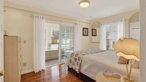 A bedroom with a bed, a nightstand, a lamp, a wardrobe, and a sliding glass door leading to a balcony. - Private Coastal 3 BD Residence in Ocean Park (Old Orchard Beach)