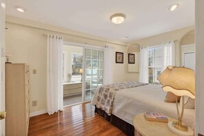 Ein Schlafzimmer mit Bett, Nachttisch, Lampe, Kleiderschrank und einer Glasschiebetür, die auf einen Balkon führt.