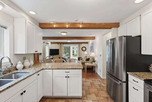Eine Küche mit weißen Schränken, Granit-Arbeitsplatten, einem Edelstahl-Kühlschrank und einem Essbereich mit Tisch und Stühlen.