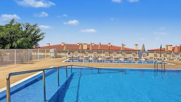 A swimming pool with a tiled deck, lounge chairs, and a fenced area with a no swimming sign.