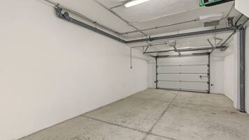 Eine saubere, leere Garage mit geschlossenem Garagentor, Betonboden und Deckenleuchten.
