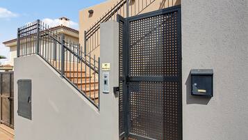 A gated entrance with a metal staircase leading to a building with a beige facade.