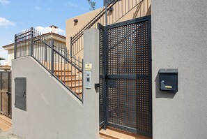 A gated entrance with a metal staircase leading to a building with a beige facade.
