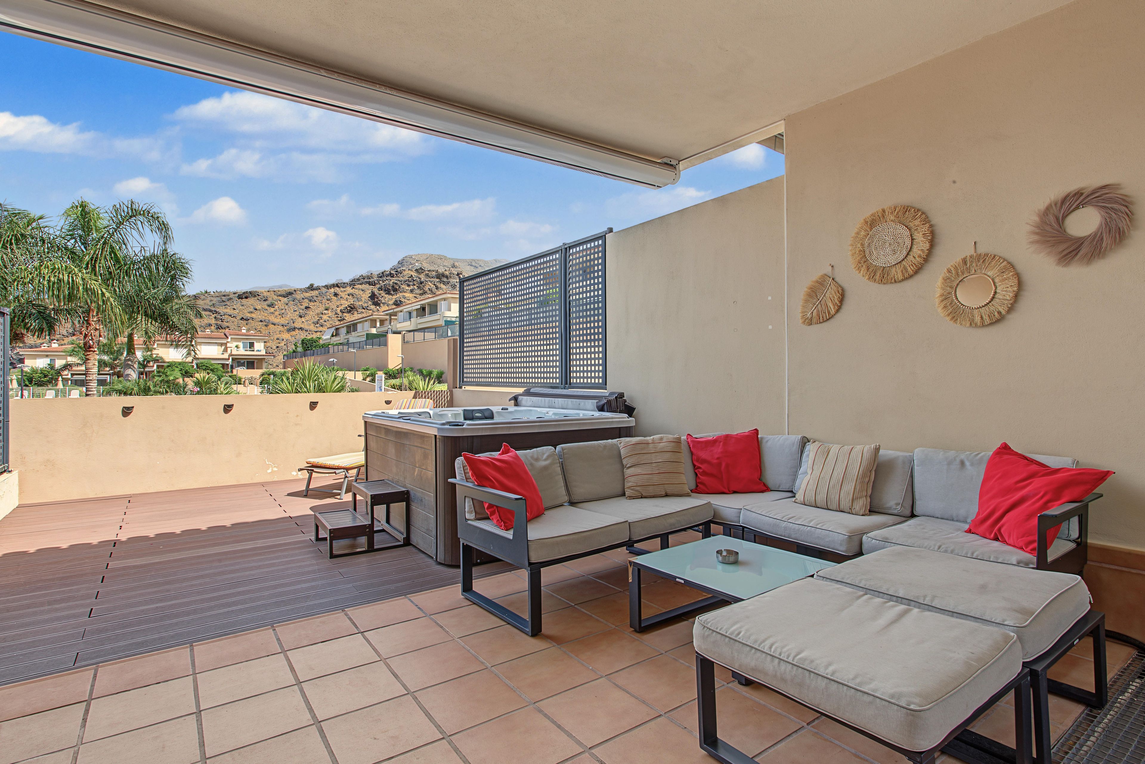 An outdoor patio with a sofa, a table, and a hot tub.
