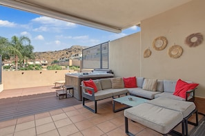 Un patio al aire libre con un sofá, una mesa y un jacuzzi.