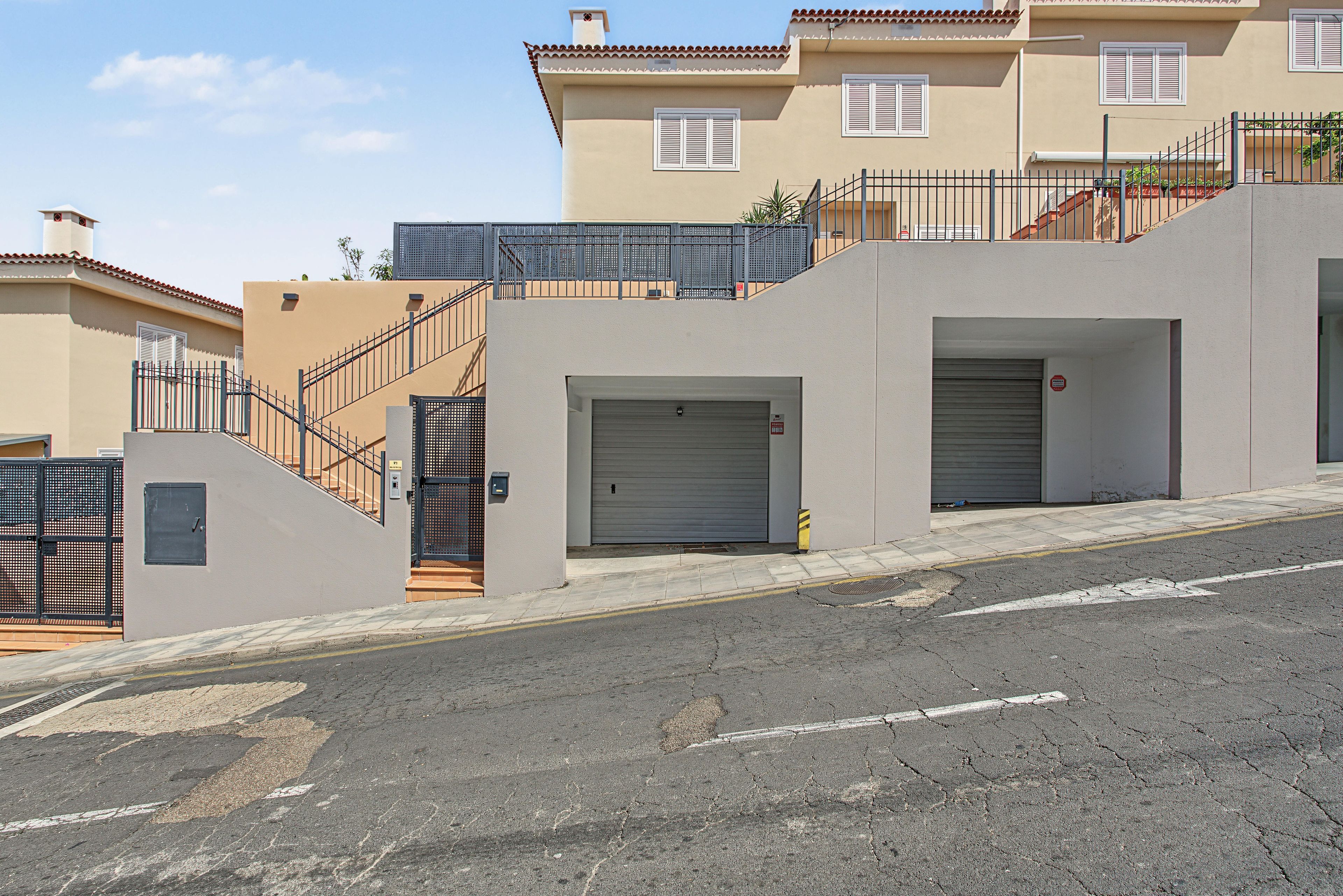 A residential building with a gated entrance, a staircase, and a garage door.