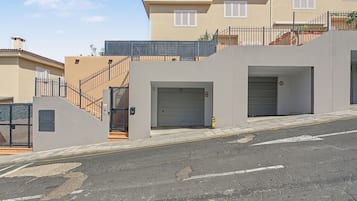 A residential building with a gated entrance, a staircase, and a garage door.