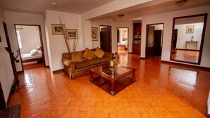 Un salón amplio con un sofá marrón, una mesa de centro y un espejo grande que refleja la habitación.
