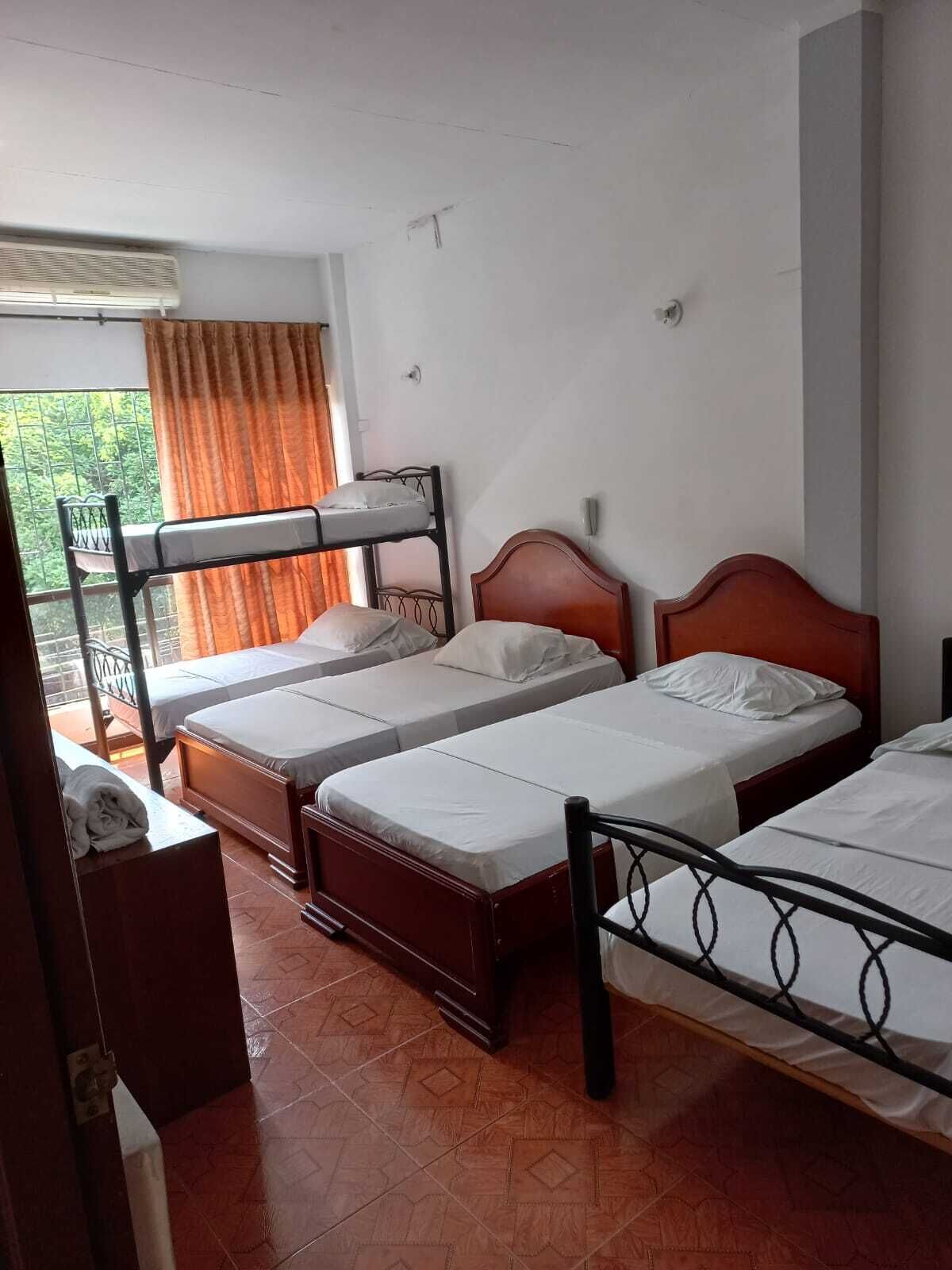 Habitación tipo dormitorio con literas, una cama individual, una ventana con cortinas y suelo de baldosas.