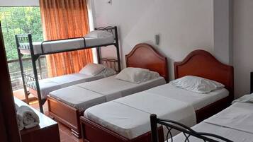Habitación tipo dormitorio con literas, una cama individual, una ventana con cortinas y suelo de baldosas.