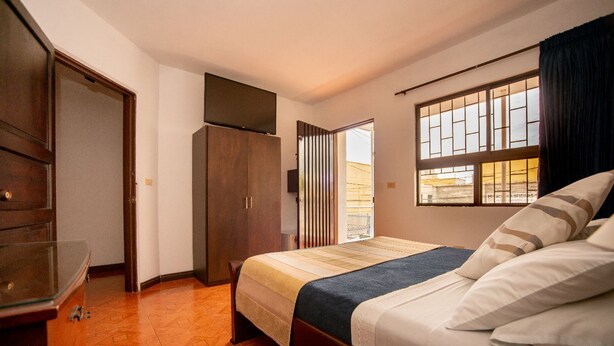 Un dormitorio con cama, armario, espejo y ventana con vistas.