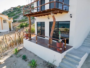 A modern two-story house with a balcony, potted plants, and a staircase.