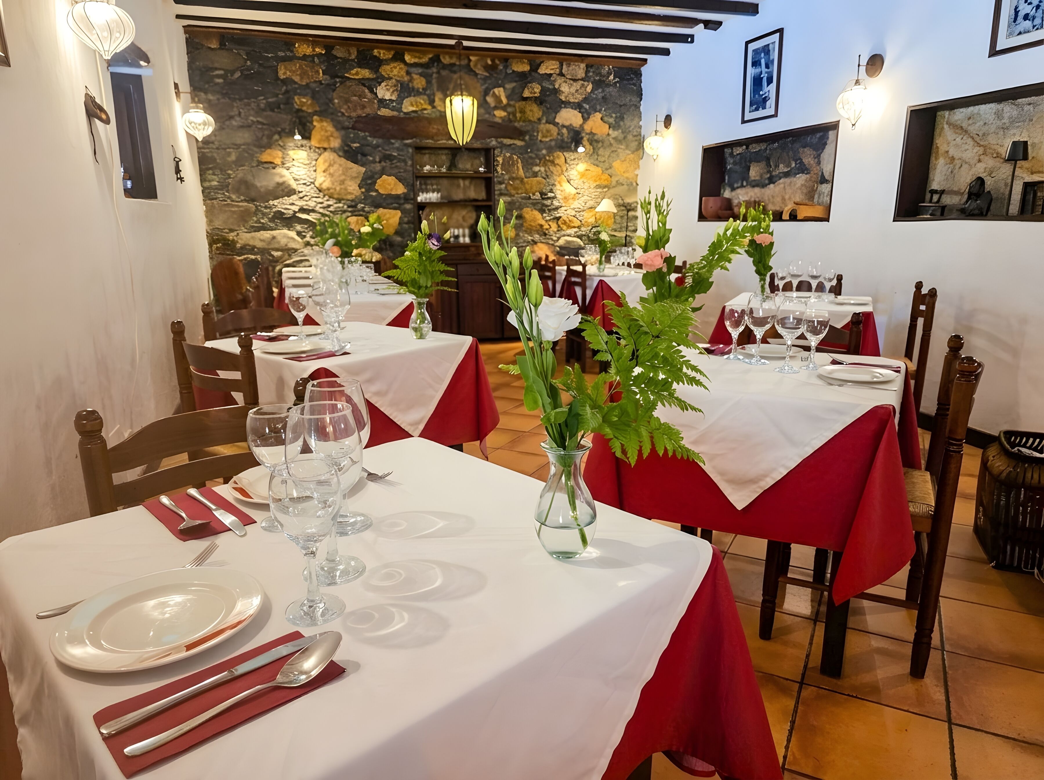 Ein Restaurant mit gedeckten Tischen, Steinwänden und warmer Beleuchtung.