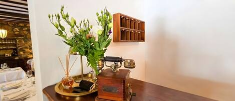 A wooden table with a vintage radio, a glass vase with flowers, and a tray with a candle.