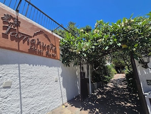 A hotel entrance with a sign, a gate, and a pathway leading to the building. - Hotel Rural Tamahuche (Vallehermoso)