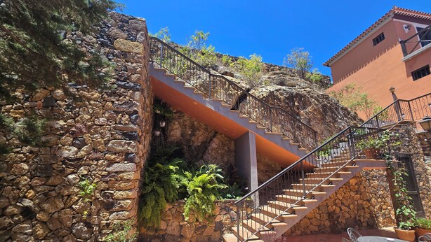 Una escalera de piedra que lleva a una terraza con plantas en macetas y mobiliario de exterior.