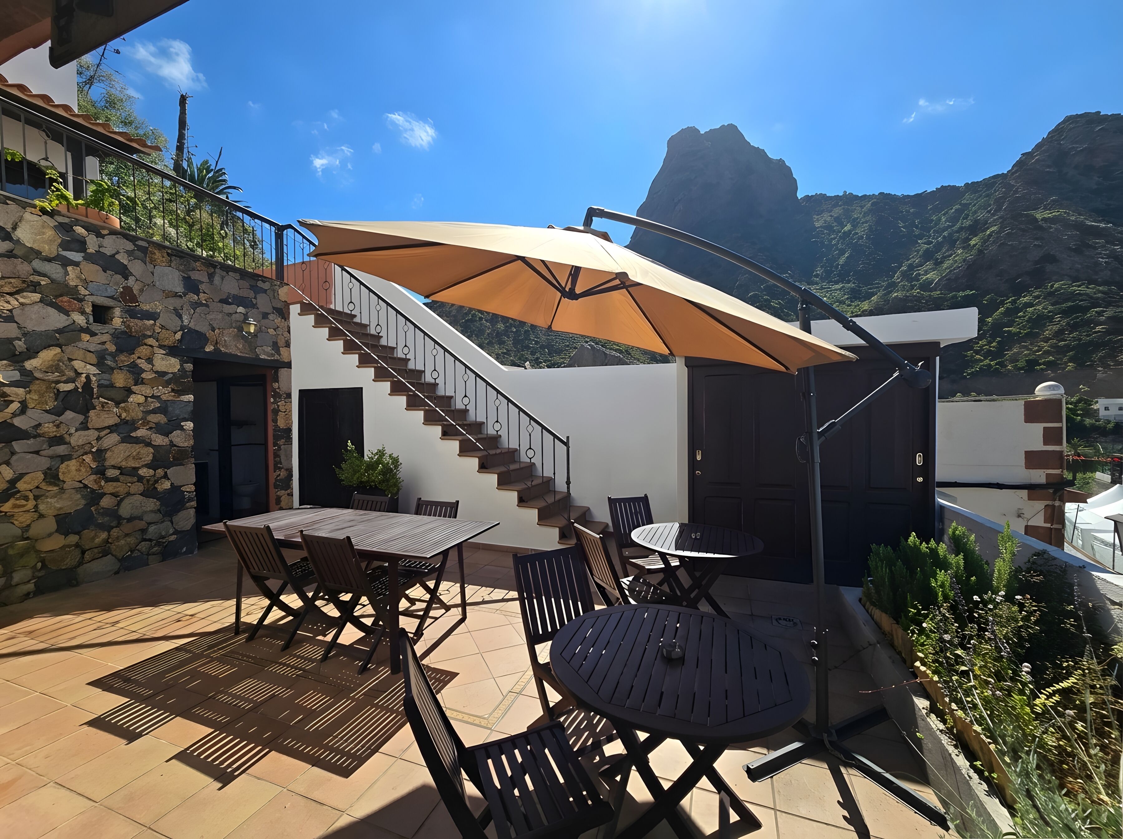 Um pátio com mobiliário externo, uma escadaria e vista para as montanhas.