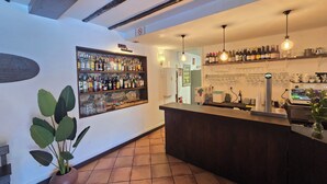 Zona de bar con estantes llenos de botellas de licor, una máquina de café y una planta en maceta.