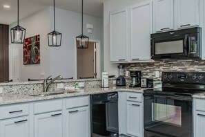 A modern kitchen with white cabinets, a black microwave, a built-in oven, a dishwasher, and a coffee maker. - 5BR Private Pool Home at Veranda Palms (Kissimmee)