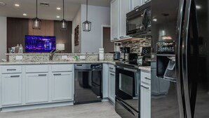 A modern kitchen with white cabinets, a black refrigerator, a microwave, and a dishwasher. - 5BR Private Pool Home at Veranda Palms (Kissimmee)