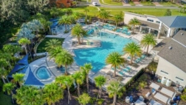 A resort with a central swimming pool, multiple lounge areas, and a variety of trees. - 5BR Private Pool Home at Veranda Palms (Kissimmee)