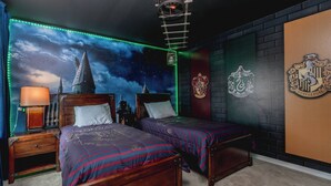 A room with two beds, a nightstand, a lamp, a wall with a crest, and a starry sky mural. - 5BR Private Pool Home at Veranda Palms (Kissimmee)