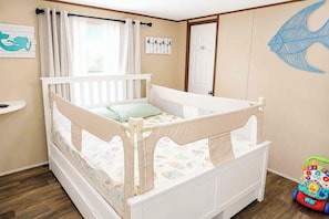 A child’s bedroom with a crib, a toy, and a wall decoration.